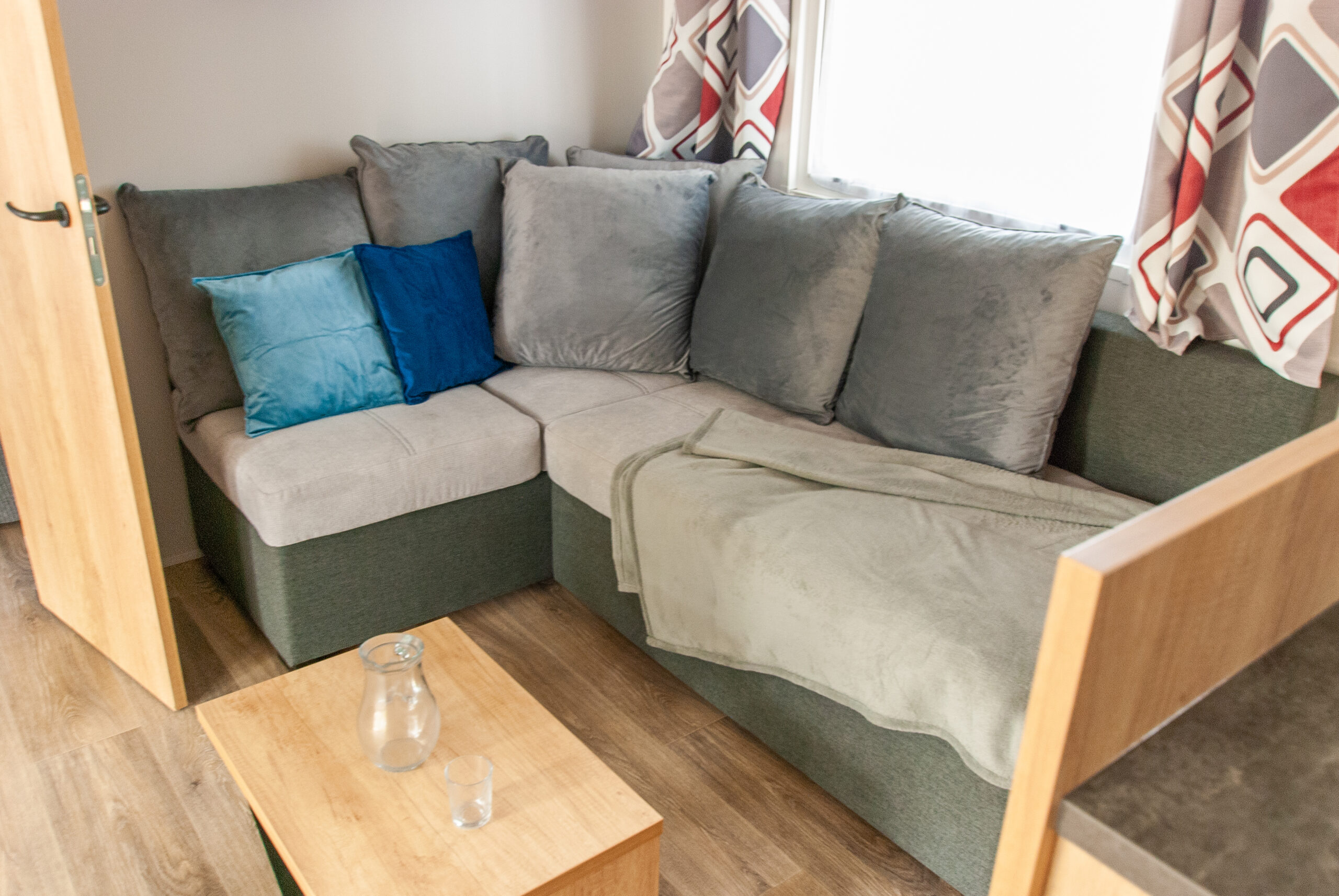 Interior espacioso de la autocaravana Rapid'home Elite 902, con cómodo sofá y mesa de centro en la habitación principal, ideal para vacaciones en la región de las Landas