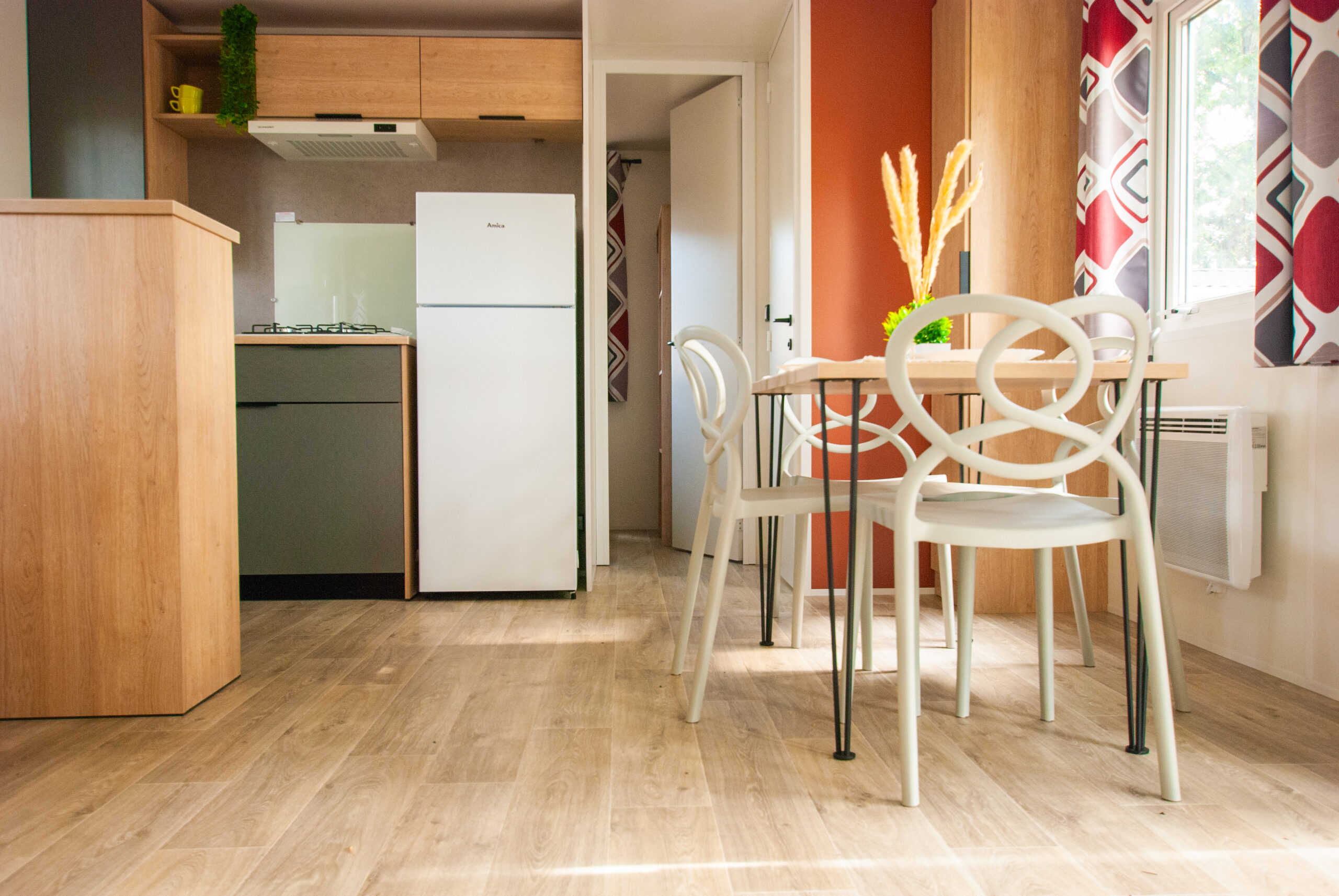 Intérieur mobil home Rapid'home LO872 à vendre dans les Landes - salle à manger avec table ouverte, cuisine accessible, portes de la salle de bains et chambre d'amis pour enfants