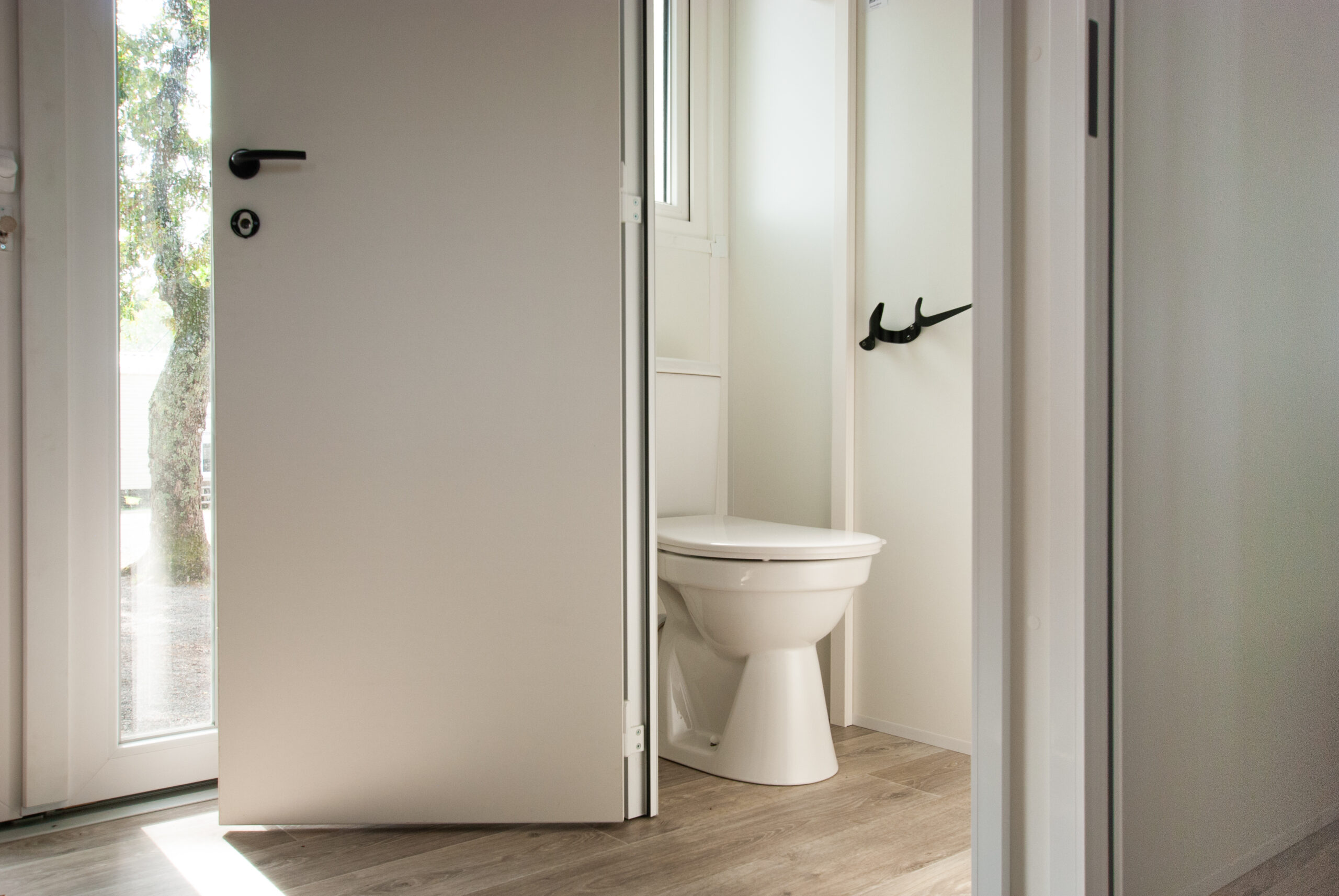 Intérieur mobil home Rapid'home LO872 à vendre dans les Landes : coin WC lumineux avec porte ouverte et fenêtre au-dessus pour une ventilation agréable.