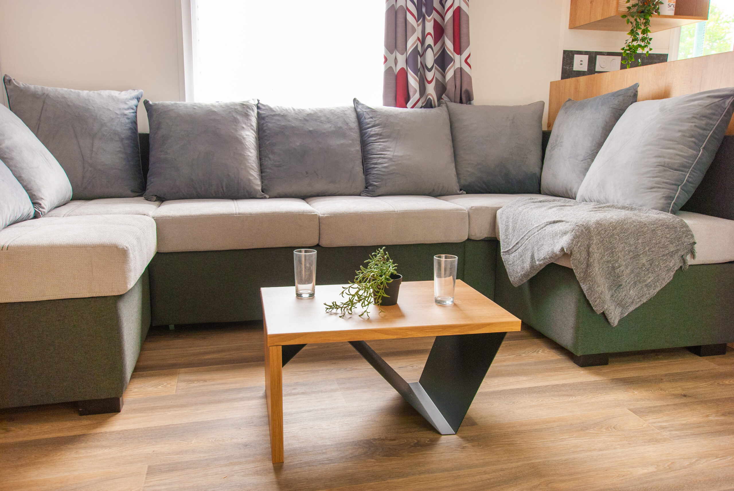 Intérieur du mobil home Rapid'home Élite 1040 avec vue sur le canapé du salon et la table basse, parfait pour des vacances conviviales en famille ou entre amis dans les Landes, avec 2 salles de bains et 3 chambres.