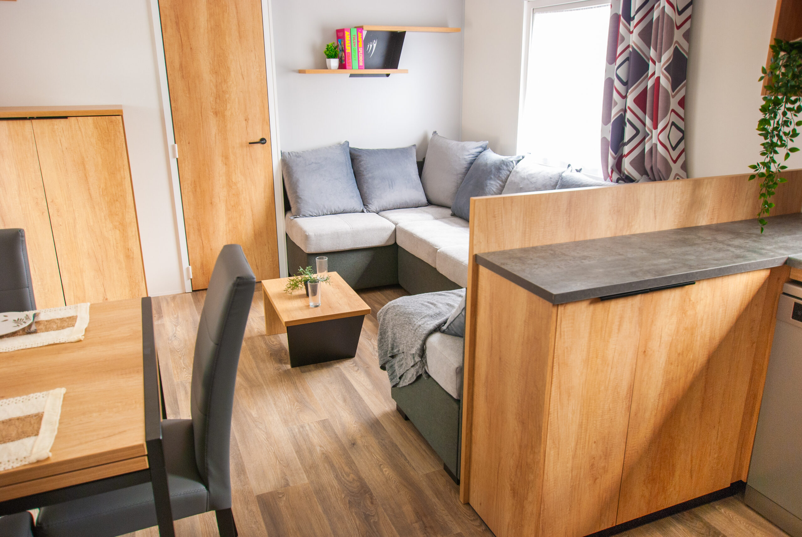 Intérieur chaleureux d'un mobil home Rapid'home Élite 1040 avec canapé confortable, finition en bois, 2 salles de bains et 3 chambres, en vente dans les Landes