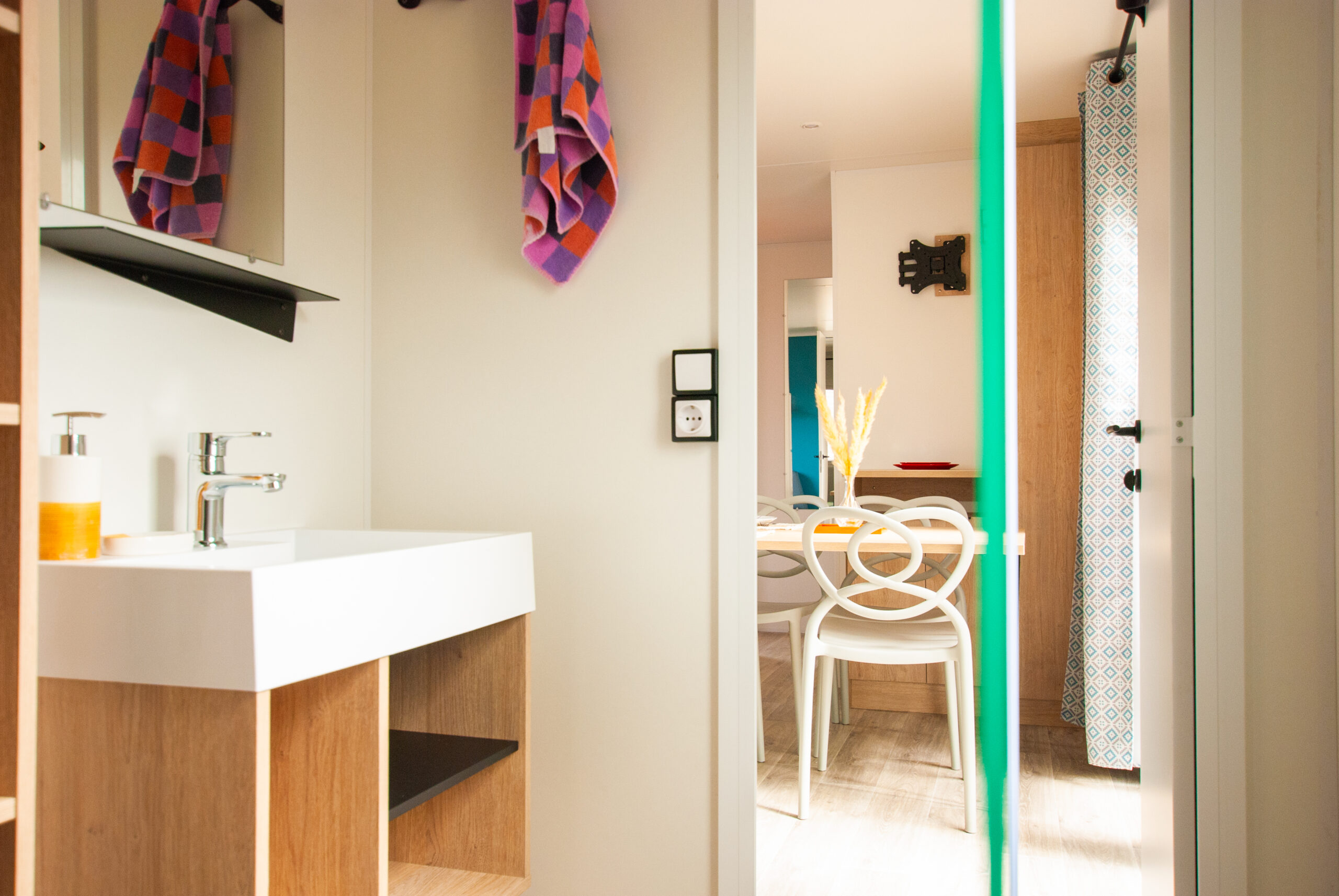 Salle de bain lumineuse dans un mobil home Rapid'home Lodge 83 à vendre dans les Landes, vue depuis la douche sur le lavabo et la salle à manger