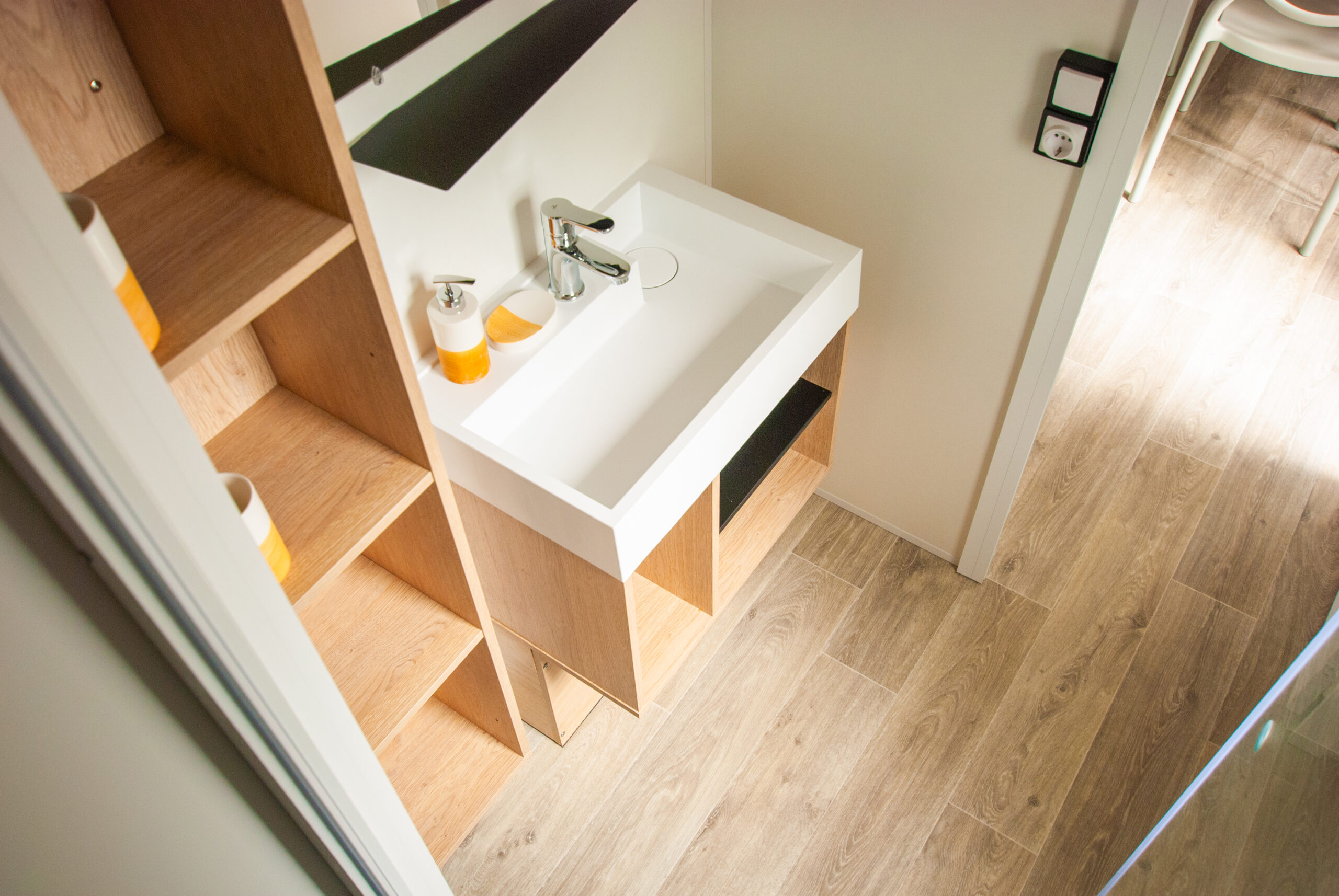Intérieur d'un mobil home Rapid'home lodge 83 à vendre dans les Landes - Salle de bain moderne avec lavabo, nombreux rangements pratiques et miroir, offrant un confort optimal