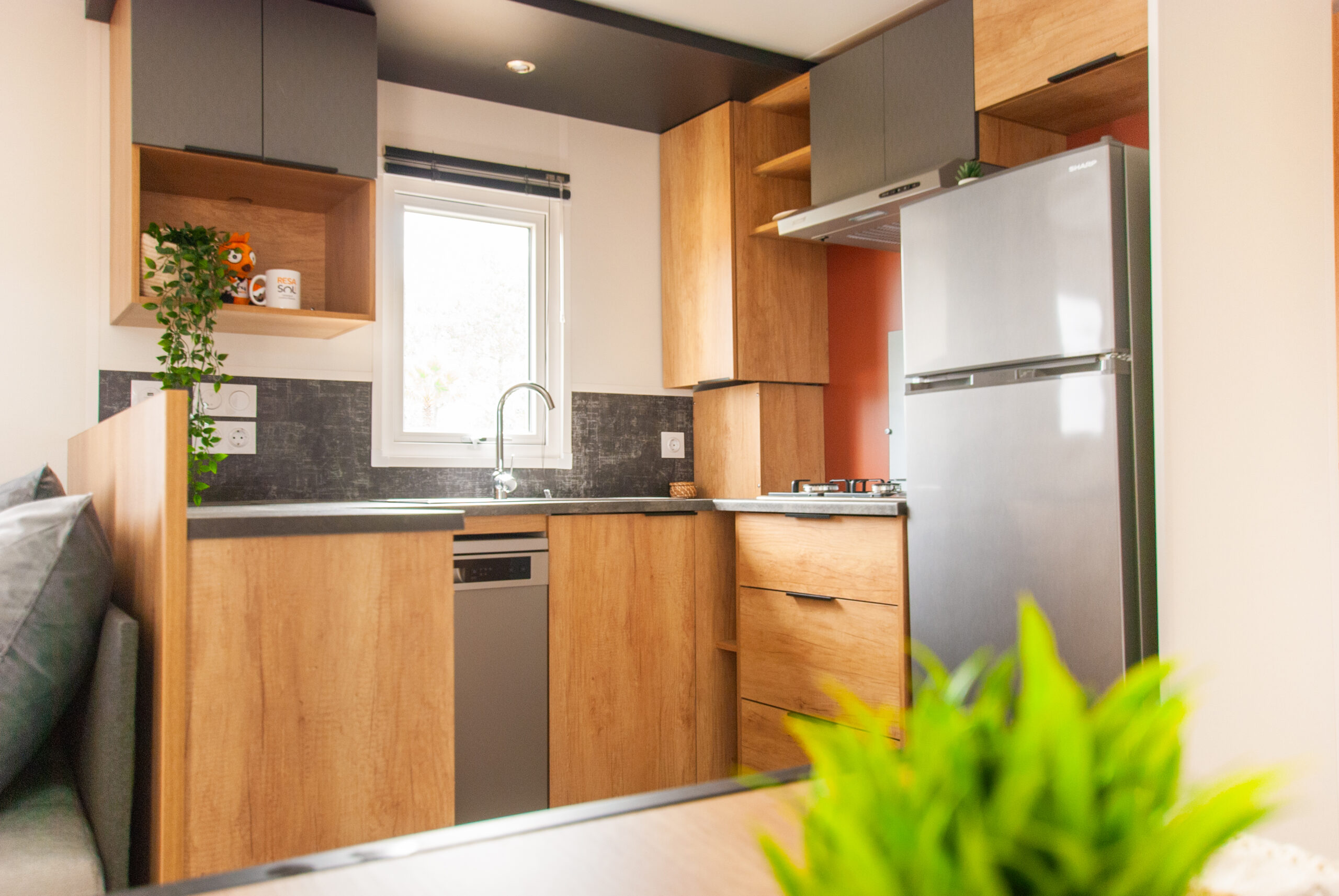 Vue de la cuisine moderne bien équipée du mobil home Rapid'home élite 1040, 2 salles de bains et 3 chambres, à vendre dans les Landes, avec une table de salle à manger accueillante.