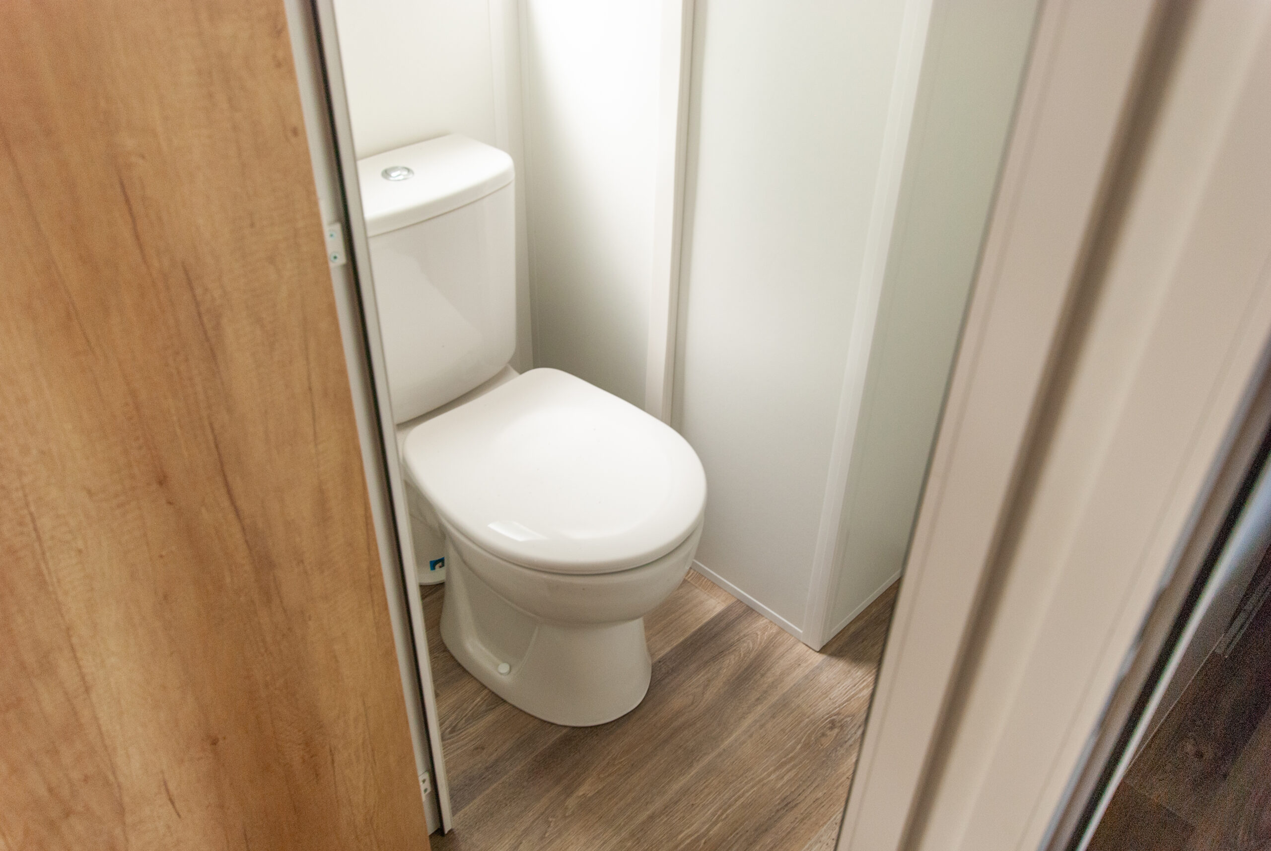 Interior de la autocaravana Rapid'home Elite 902 con WC separado, ventana y puerta para un confort óptimo, en venta en la región de las Landas en Francia